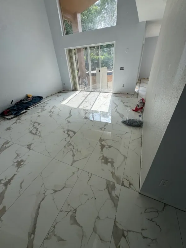 Bright room viewed from a doorway with white gray-veined flooring leading toward windows