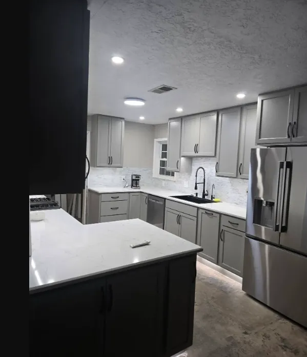 Kitchen corner with dark base cabinets, a pale countertop, stainless appliances, and a light floor