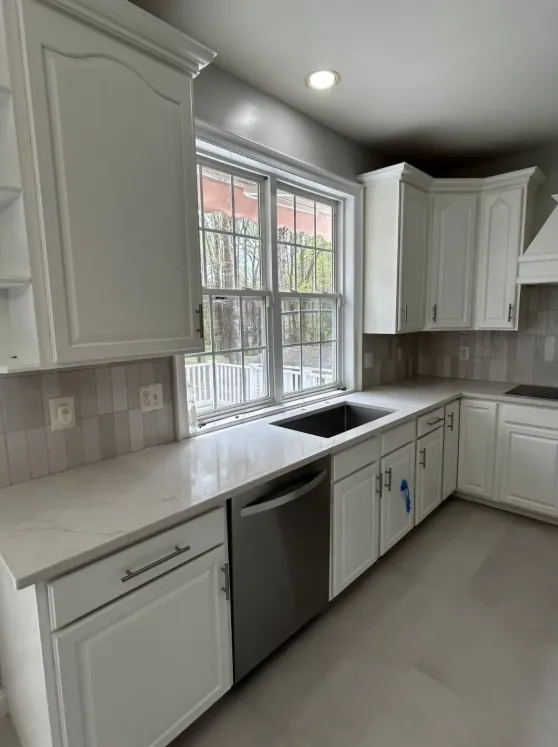 Light kitchen with white cabinetry, bright countertops, a window, and medium-brown wood-look flooring